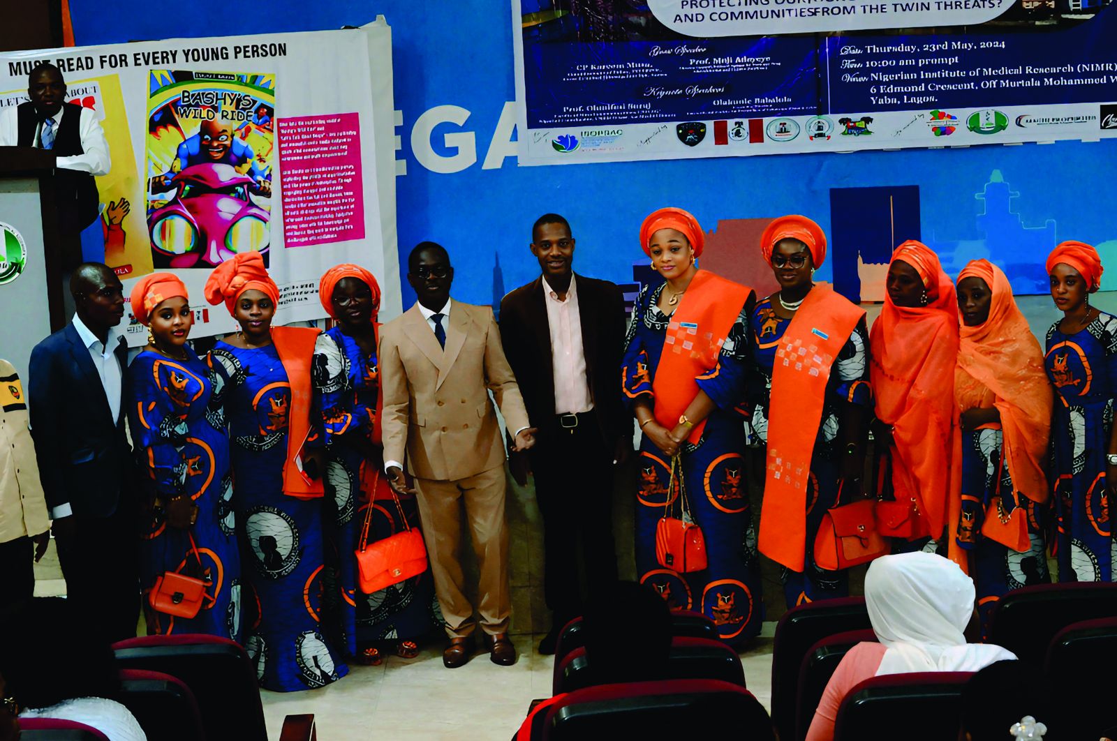 Delegates in orange with the organisers in front of the colloquium banner